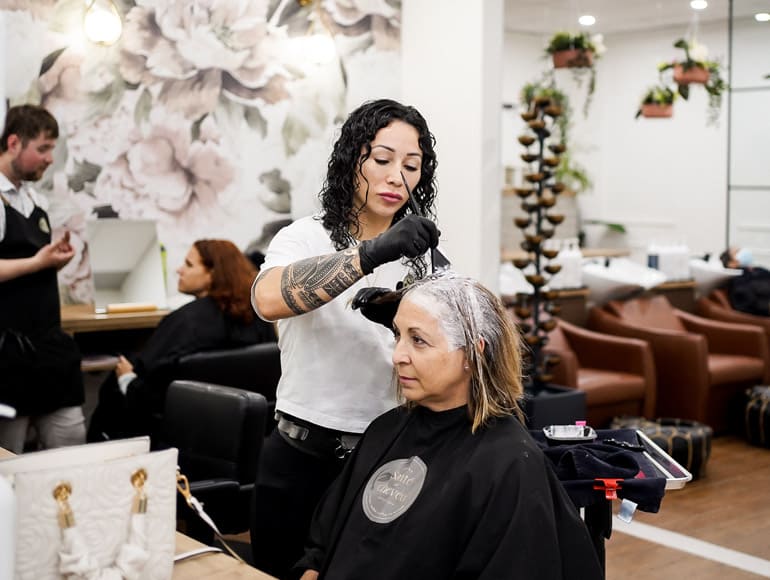 Coloriste appliquant une coloration pour couvrir les cheveux blancs