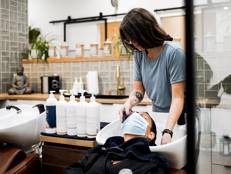 Un client au lavabo recevant un soin de coiffure naturelle