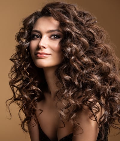 Femme avec volumateur capillaire aux cheveux bouclés